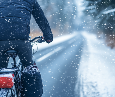 Un homme faisant du vélo en hiver pendant qu'il neige